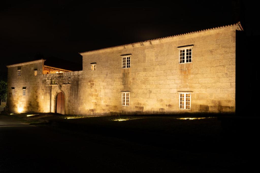 an old stone building at night with lights at Pazo de San Pedro de Bembibre in Taboada