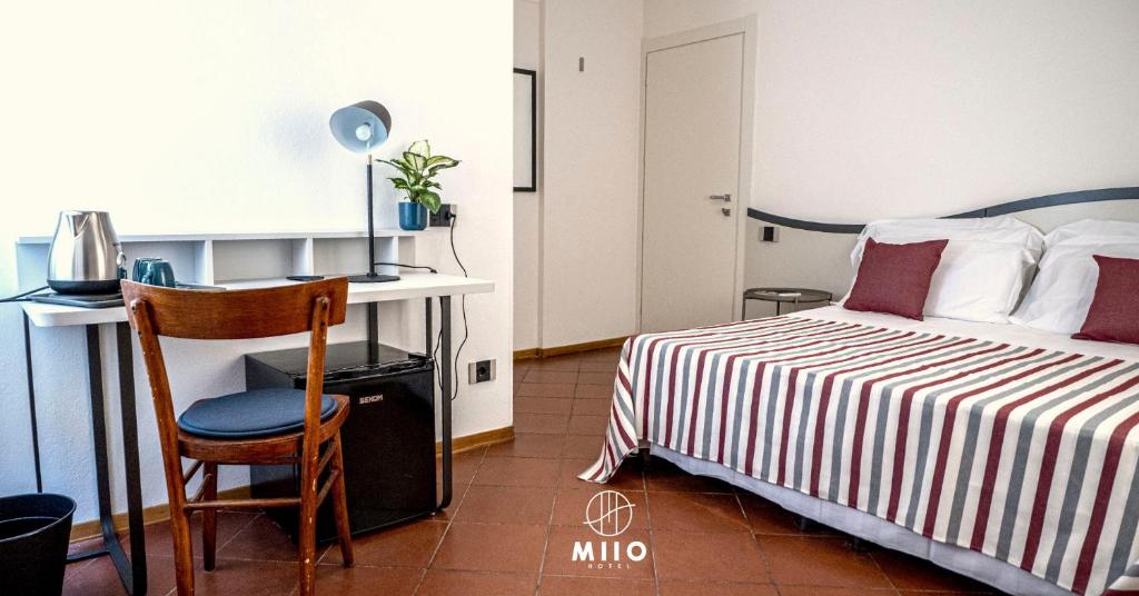 a bedroom with a bed and a desk and a chair at MIIO HOTEL in San Vincenzo