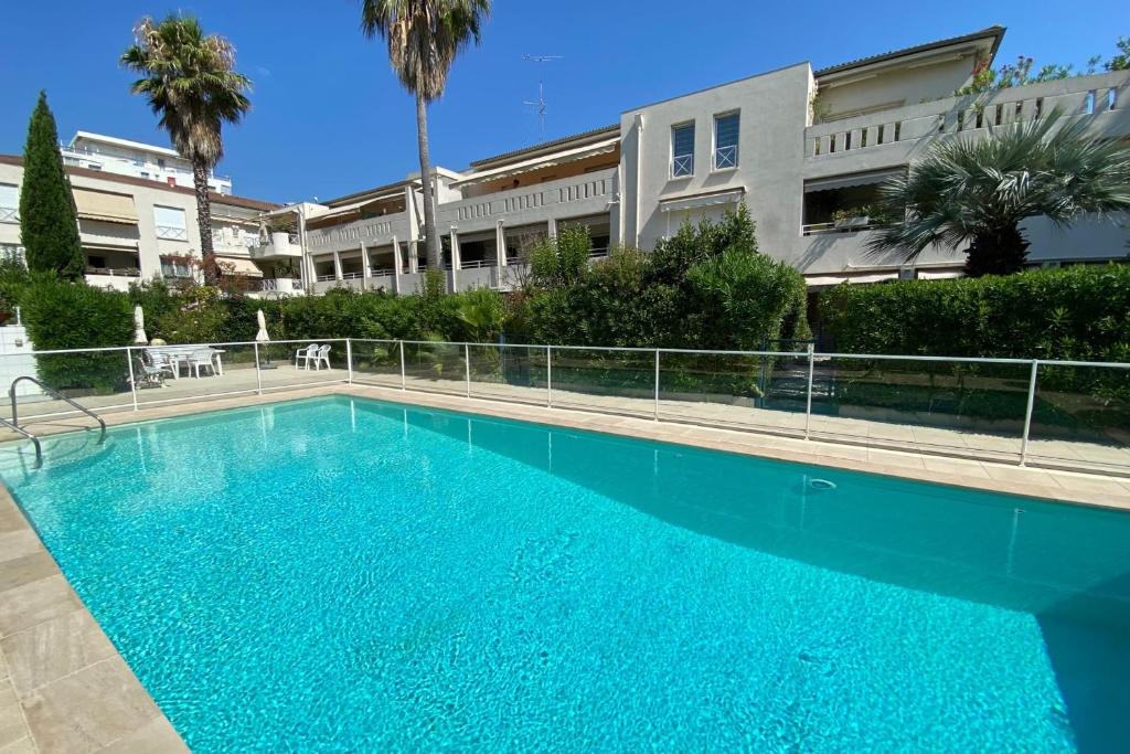 une grande piscine bleue devant un immeuble dans l'établissement Appartement Basse Croisette - Welkeys, à Cannes
