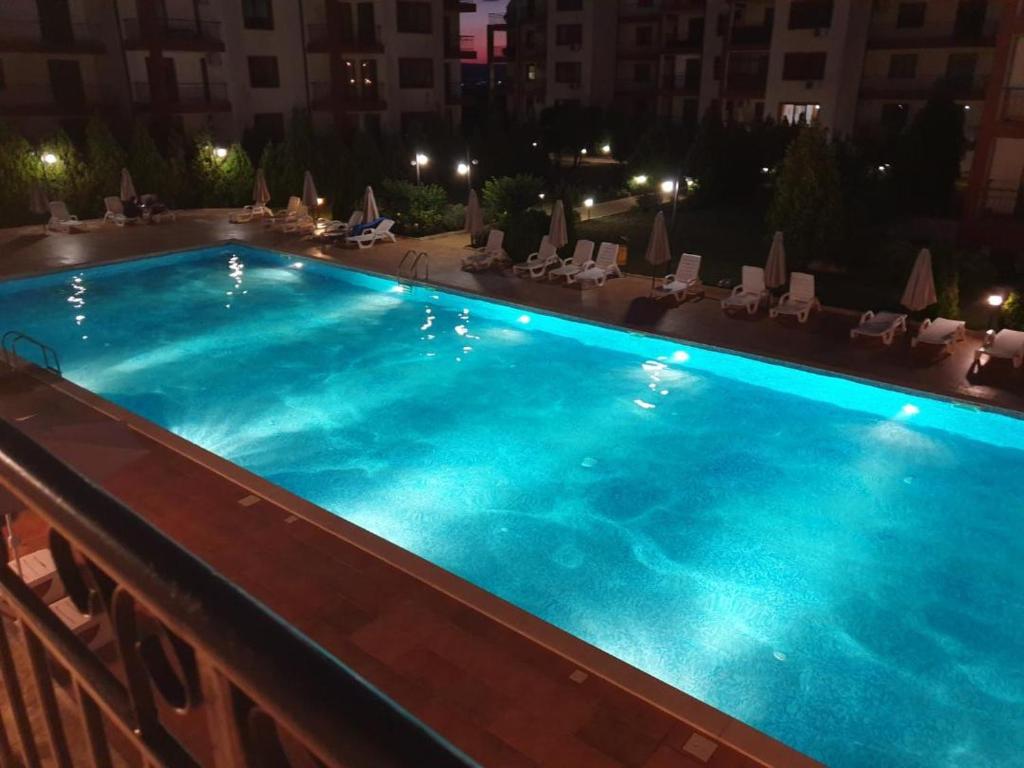 uma grande piscina à noite com cadeiras e um edifício em Famagusta Antoniya em Aheloy