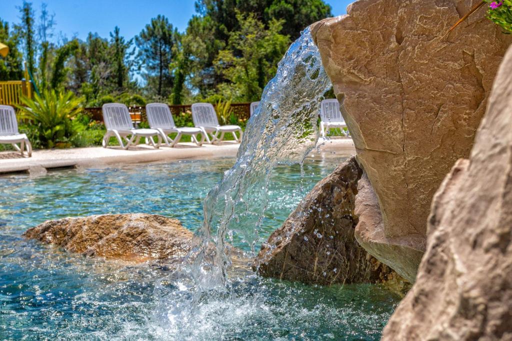 a fountain in the middle of a pool with chairs at Costa Rica Bibione Eco Resort in Bibione