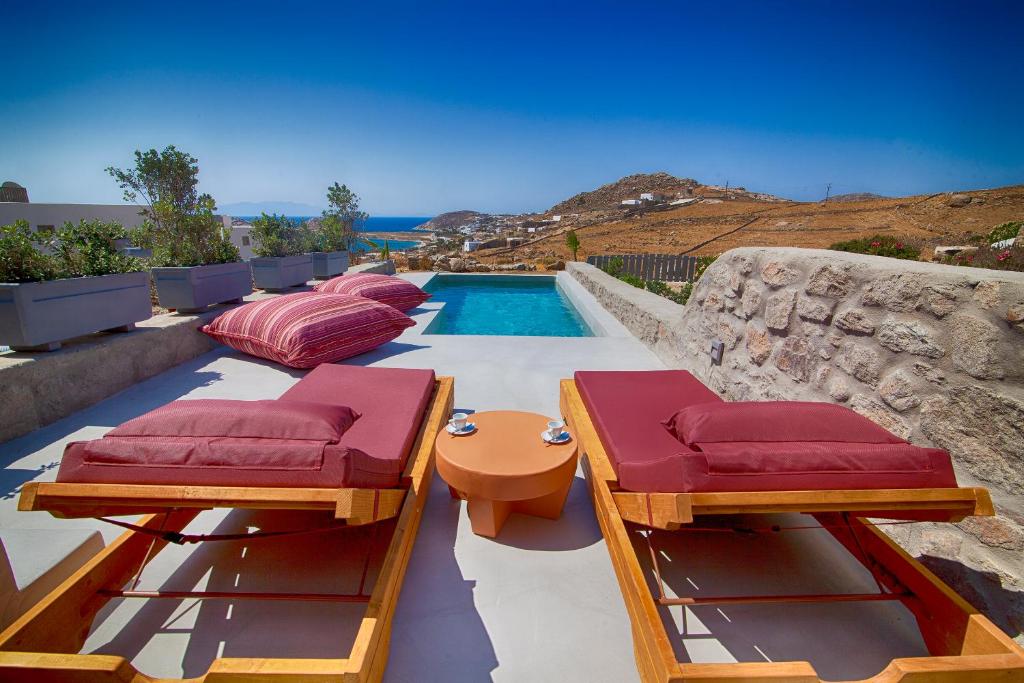 a backyard with a swimming pool with red cushioned chairs at Villa Piccolo Mondo in Kalafatis
