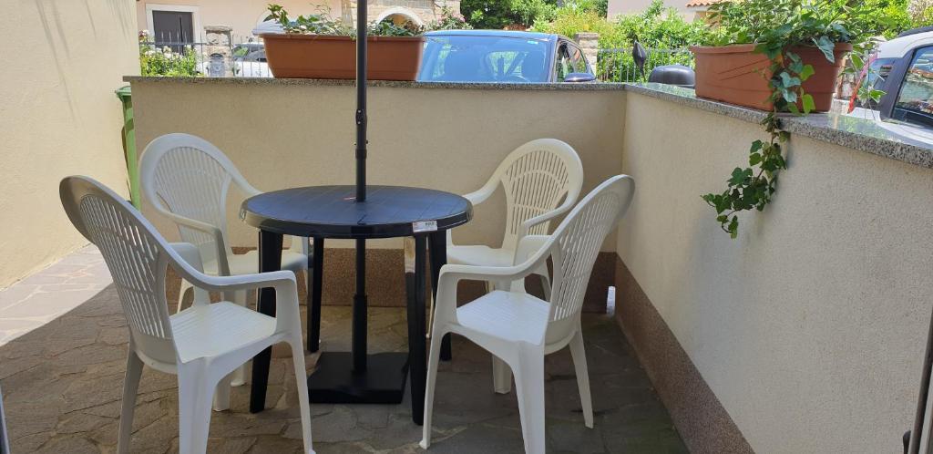 três cadeiras e uma mesa com um guarda-sol num pátio em Apartment Laguna 79 em Izola