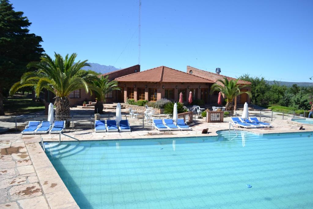 a swimming pool with blue chairs and a house at Colina del Valle in Mina Clavero