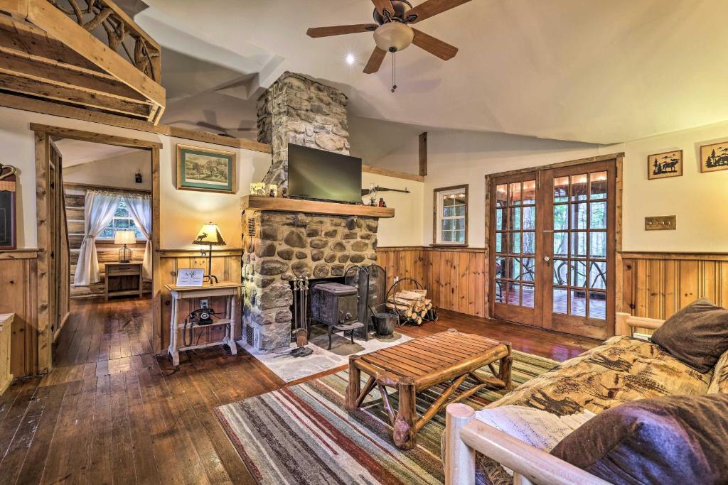 a living room with a stone fireplace and a couch at Cabin with Trails and Creek! 23 Mi to Camelback Slopes in Greentown