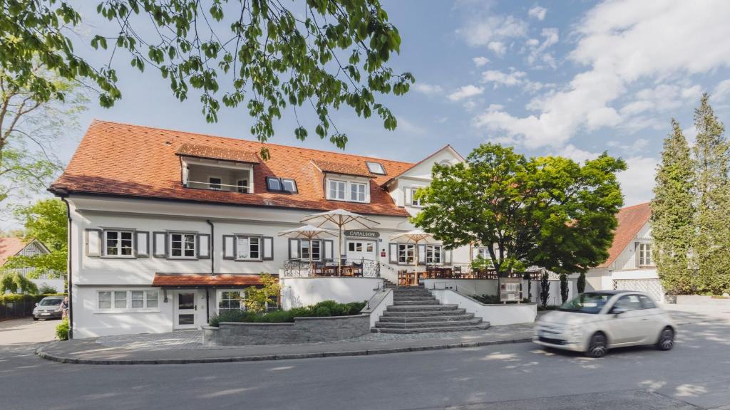 a white house with a car parked in front of it at Hotel Caraleon in Wasserburg am Bodensee