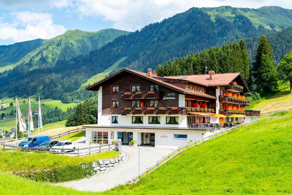 a building on a hill with mountains in the background at Hotel Gemma- Adults only in Hirschegg