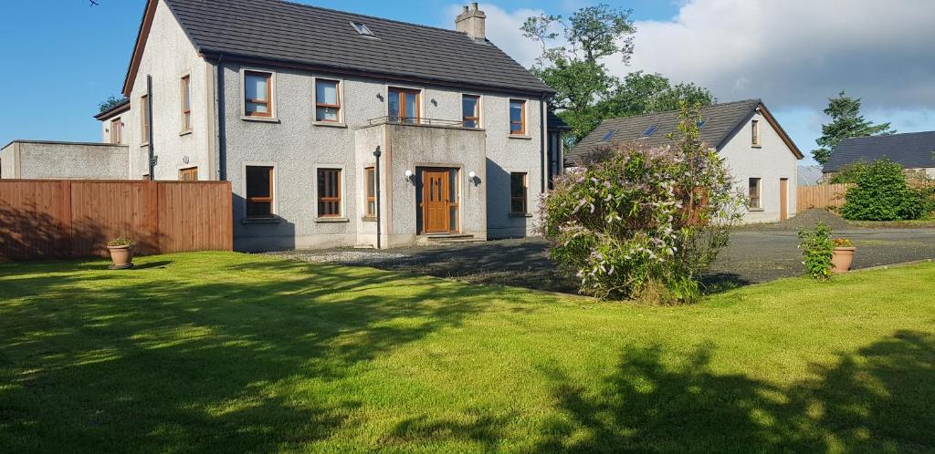 a large white house with a grass yard at Maghernahar House B&B in Ballycastle