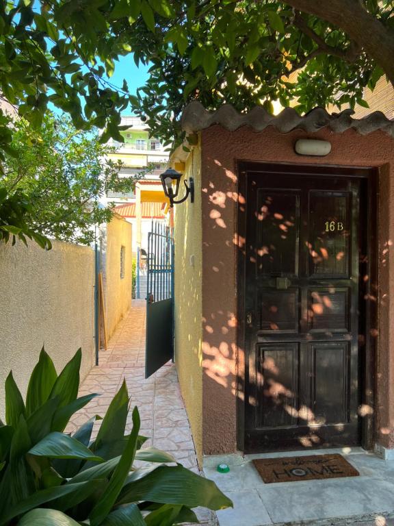 a front door of a house with a tree at Cosy guesthouse-souterrain with garden in city center in Korinthos