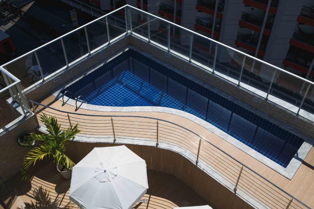 uma vista superior de uma piscina com um guarda-sol em Trópico Praia Hotel em Maceió