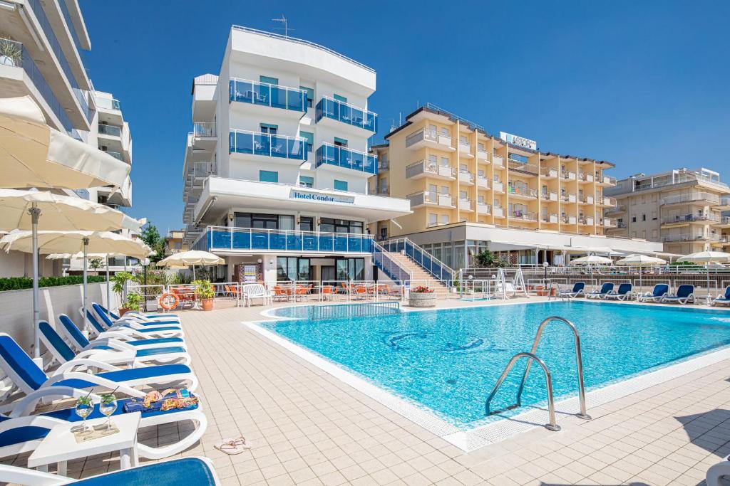 uma piscina com espreguiçadeiras e um hotel em Hotel Condor em Lido di Jesolo
