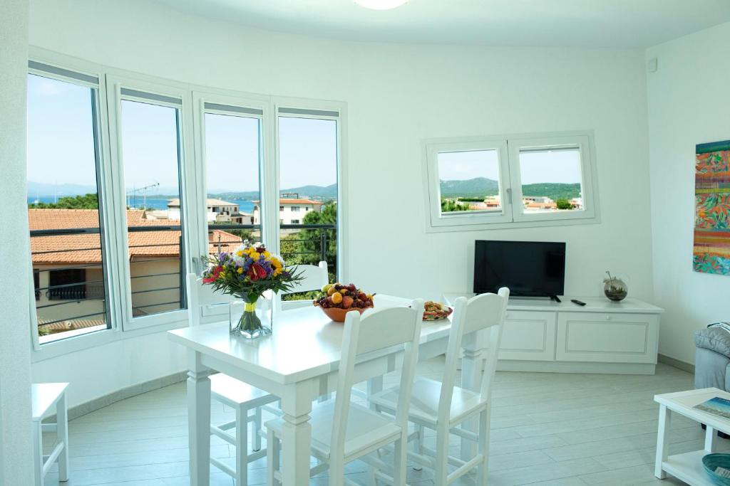 a white dining room with a table and a tv at Casa di Mario in Golfo Aranci
