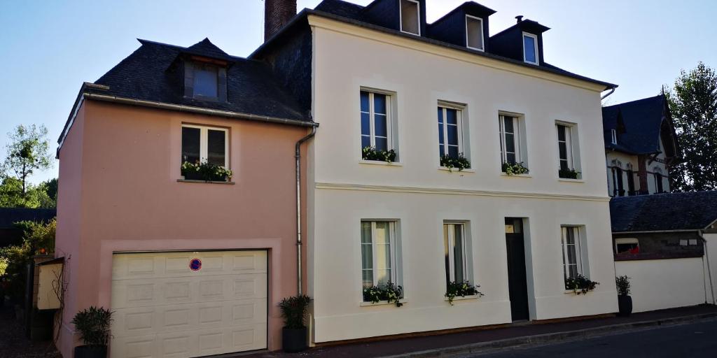een groot wit huis met een witte garage bij La Cour Du Puits Chambre Victor in Cormeilles