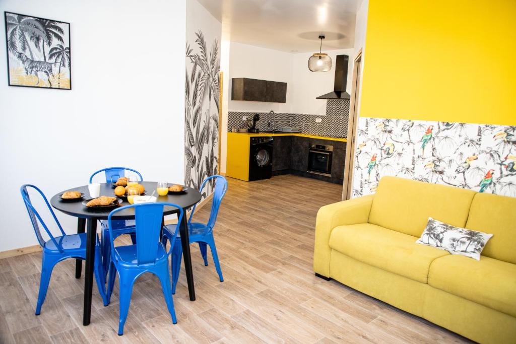 a living room with a table and a yellow couch at L&#39;Amarillo Clim Wifi Centre ville 4 pers in Lézignan-Corbières
