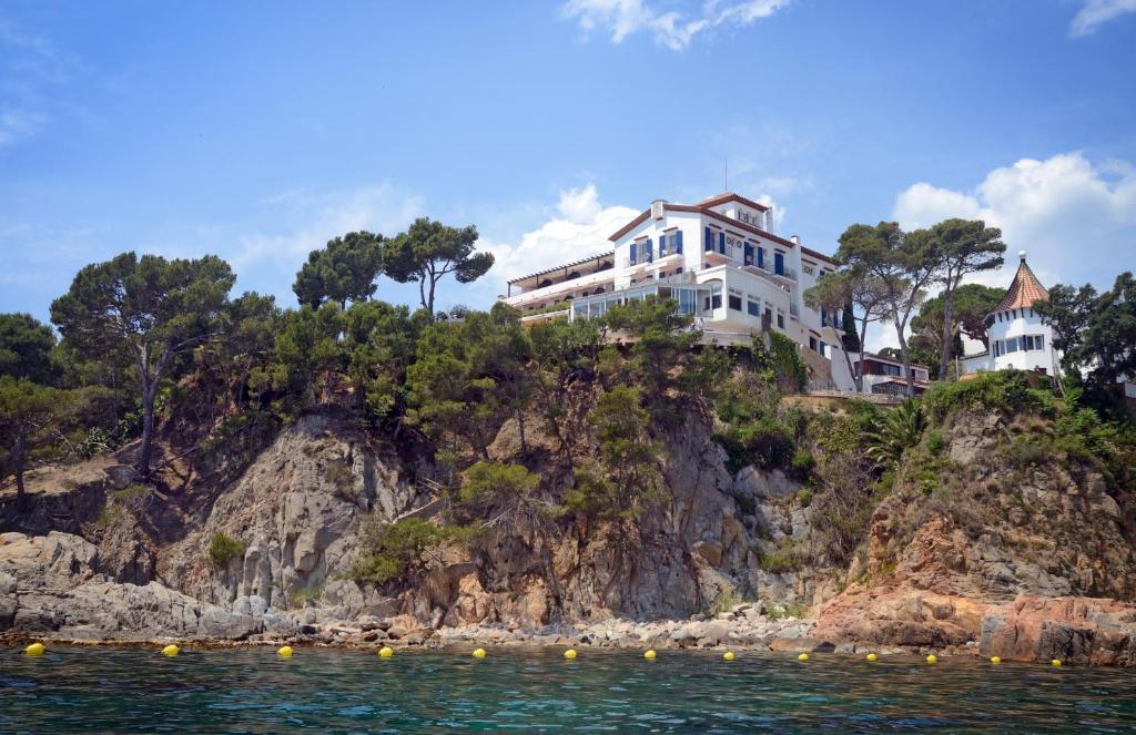 a house on a cliff next to the water at Hotel Sant Roc in Calella de Palafrugell