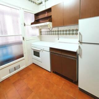 una cucina con frigorifero bianco e armadi marroni di Ruta del quijote a Campo de Criptana