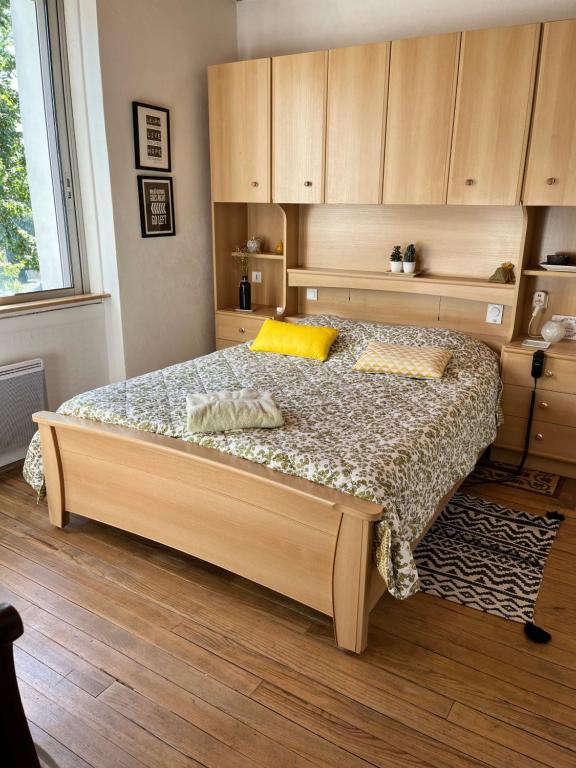 Un dormitorio con una cama grande con armarios de madera. en L appartement cosy, en Le Garric