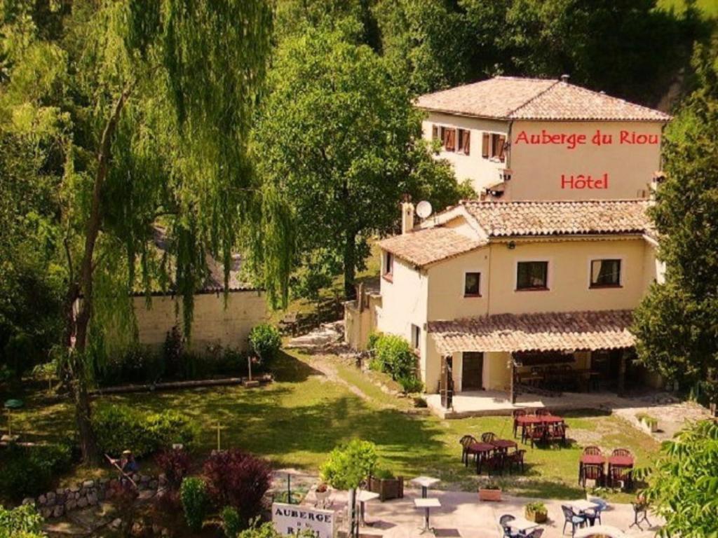 Blick auf ein Gebäude mit einem Hof mit Tischen in der Unterkunft Auberge Du Riou in Puget-Rostang