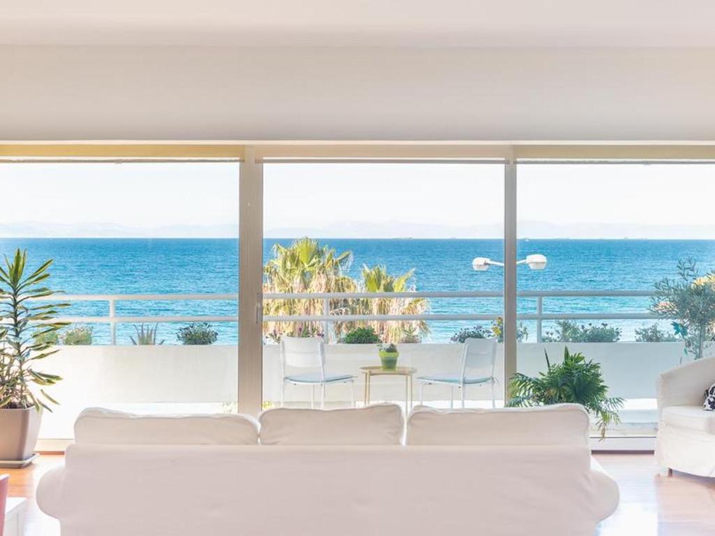 a living room with a white couch and a view of the ocean at Amazing Beach Apt Panoramic View next to Marina Alimos in Athens