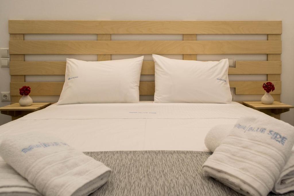 a large bed with white sheets and pillows on it at Blue Side Studios in Pefki