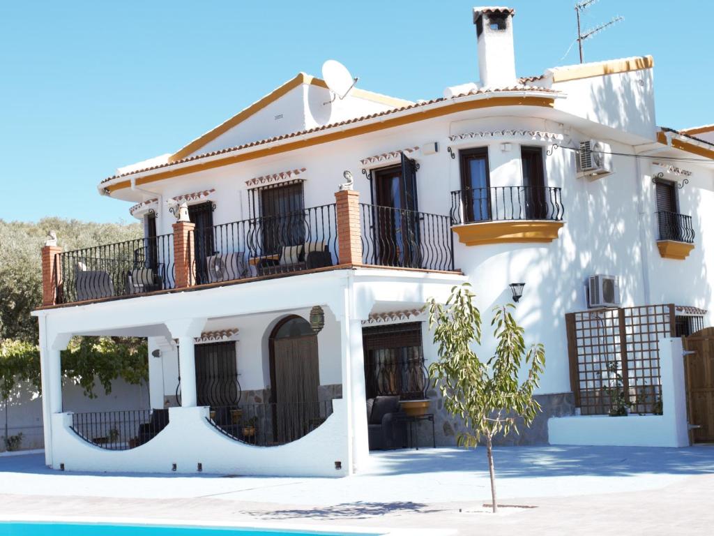 ein weißes Haus mit Balkon und einem Baum davor in der Unterkunft Casa de las Montañas in Villanueva del Trabuco