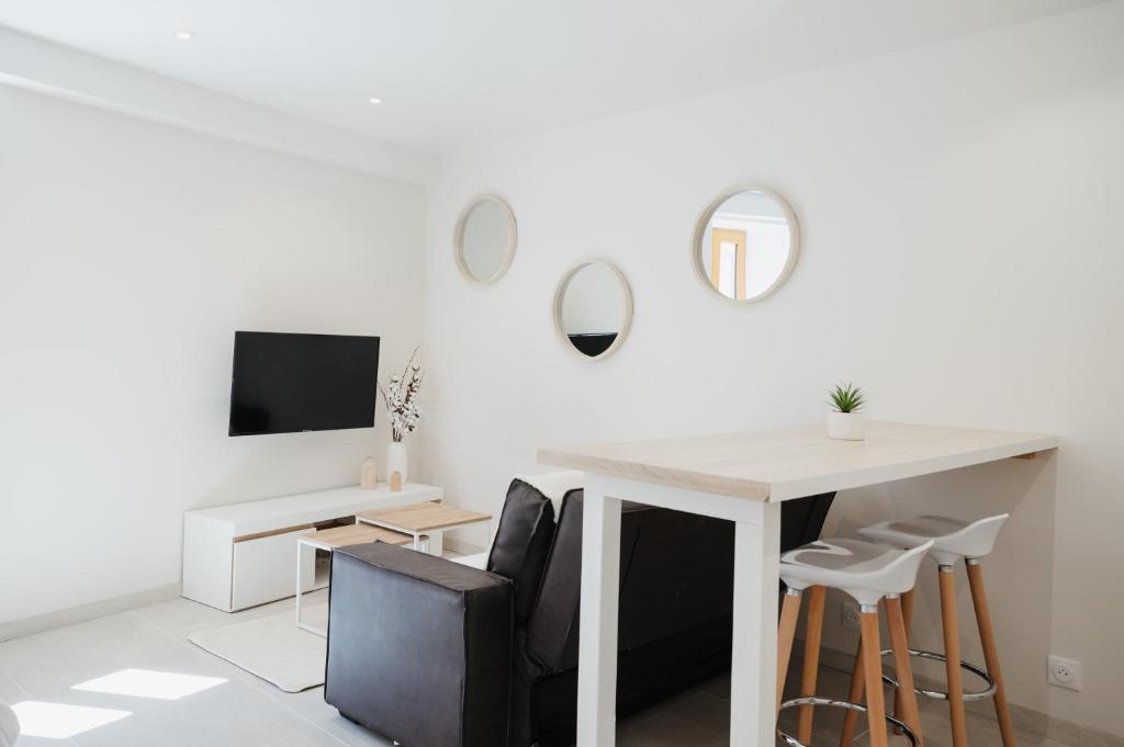 Habitación blanca con mesa, sillas y espejos en Magnifique Loft Balnéo Hammam #3 en Embrun