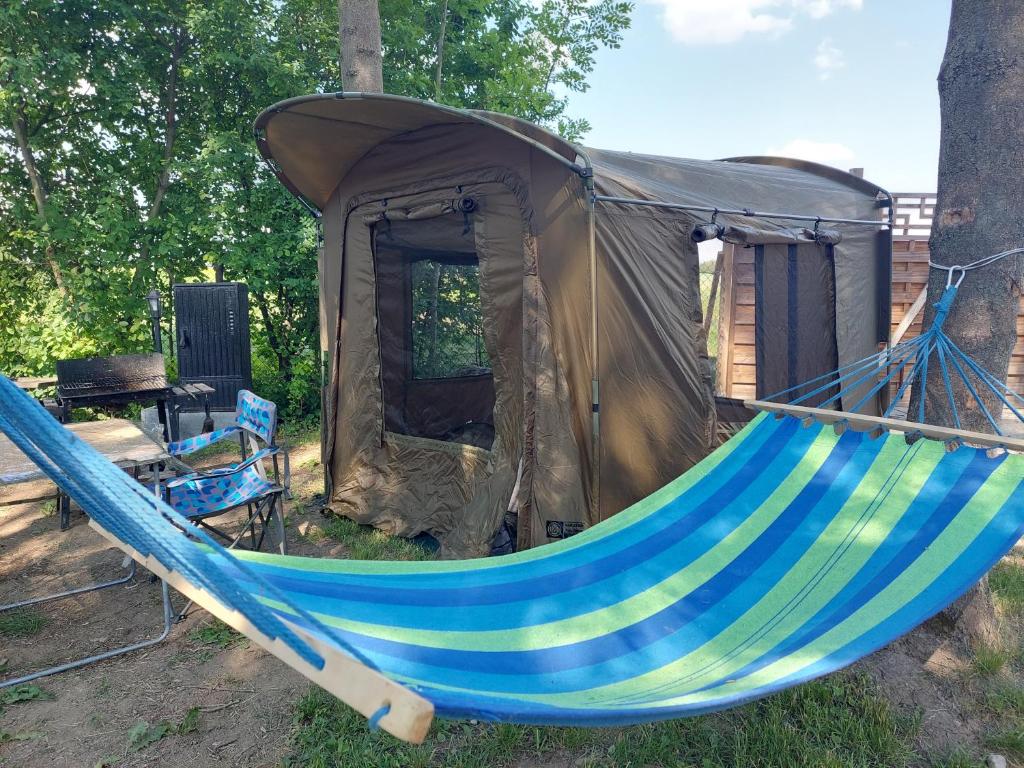 a blue and green hammock in front of a tent at Pole Namiotowe Kogutowo in Wietrzychowice