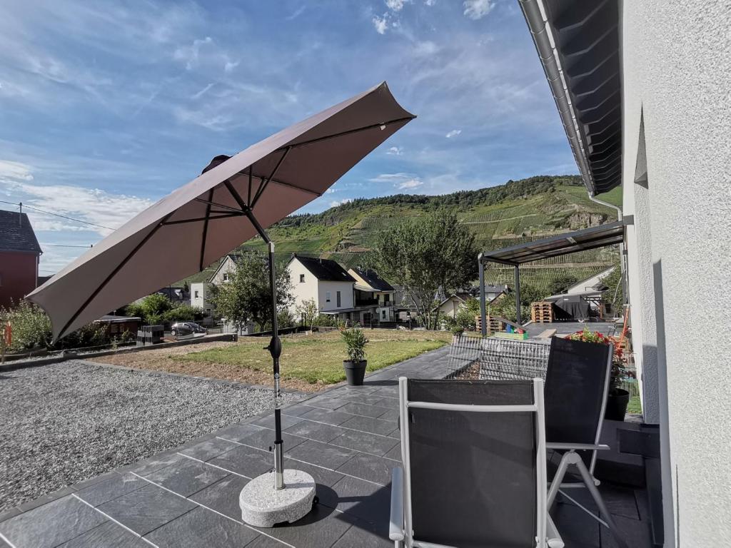 einen Regenschirm und zwei Stühle auf einer Terrasse in der Unterkunft Sonnenufer Apartment & Moselwein II in Bernkastel-Kues
