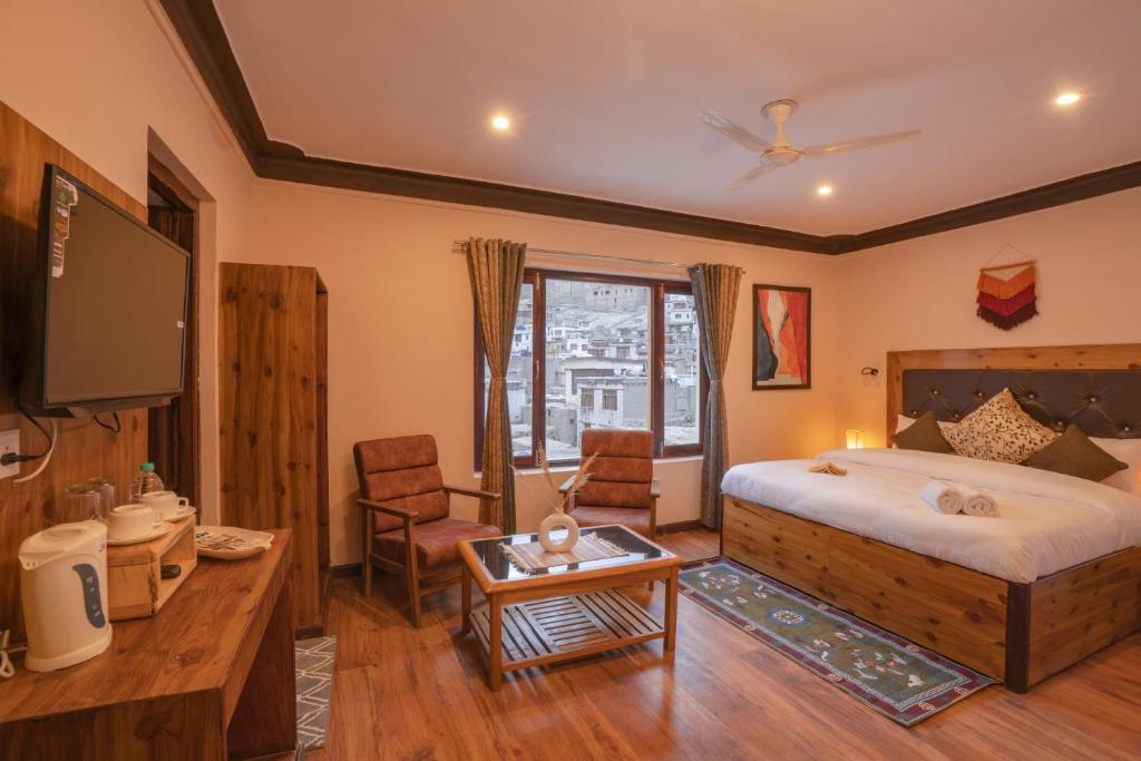 1 dormitorio con 1 cama, TV y mesa en LeHostel en Leh