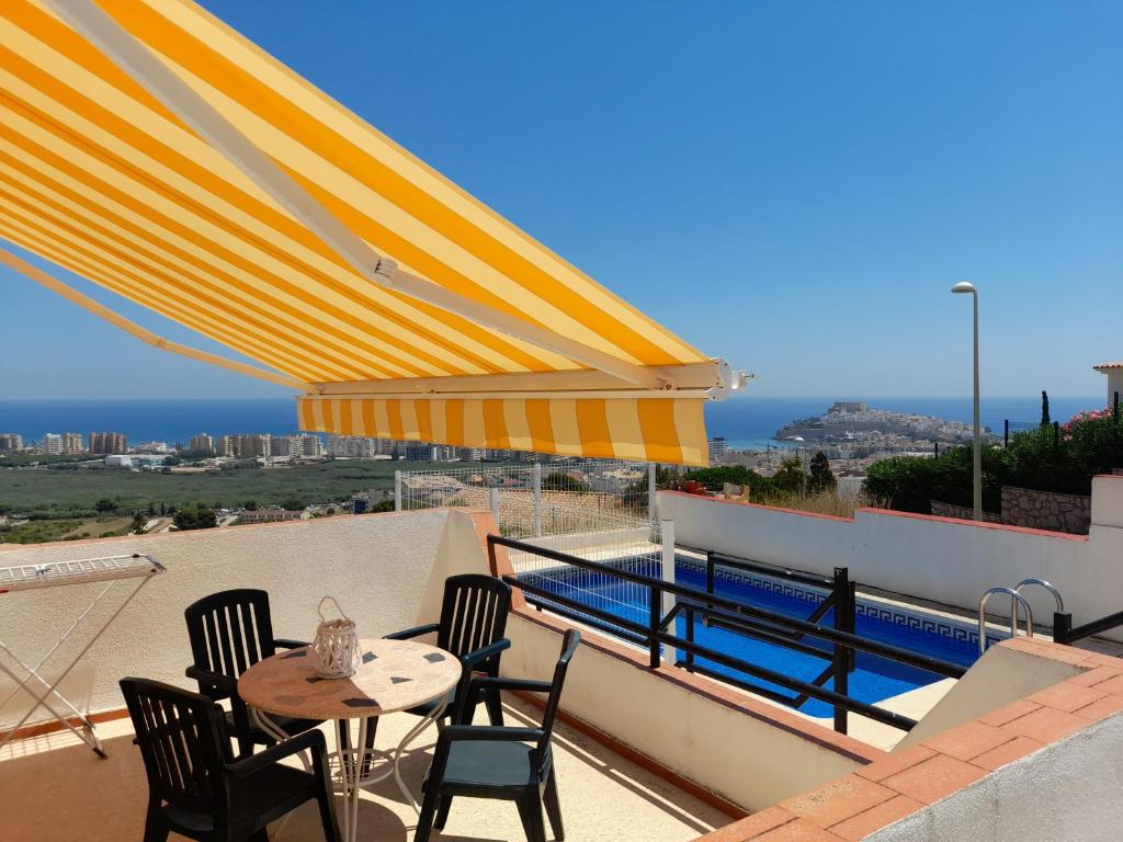 a patio with a table and chairs and a yellow umbrella at Apartamentos Vista in Peniscola