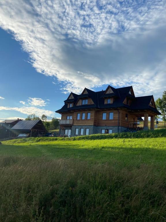ein großes Haus auf einem Feld mit bewölktem Himmel in der Unterkunft Ku Sośnie 2 in Rzepiska