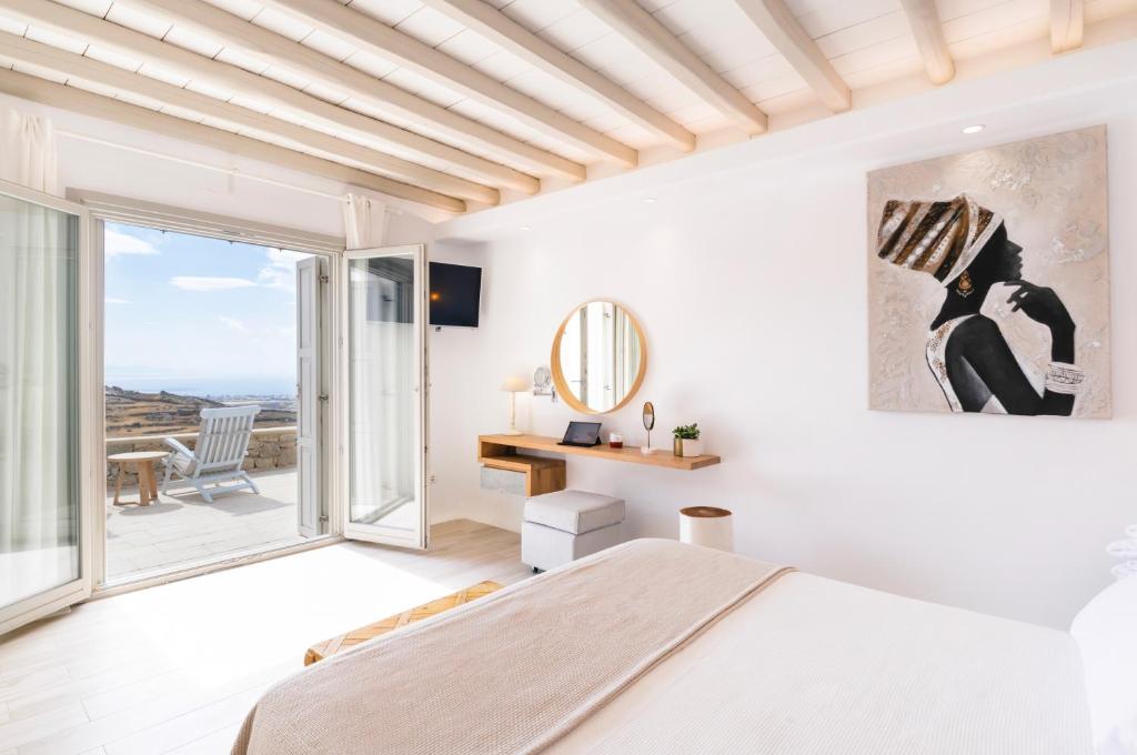 a white bedroom with a bed and a large window at Hyperion Villa by LLB Mykonos in Klouvas