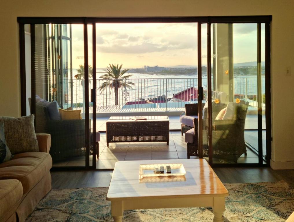 a living room with a couch and a coffee table at 'Die Braaihuis'- sleeps 6, Large Veranda, Sea Views, Central and Fabulous! in Gordonʼs Bay