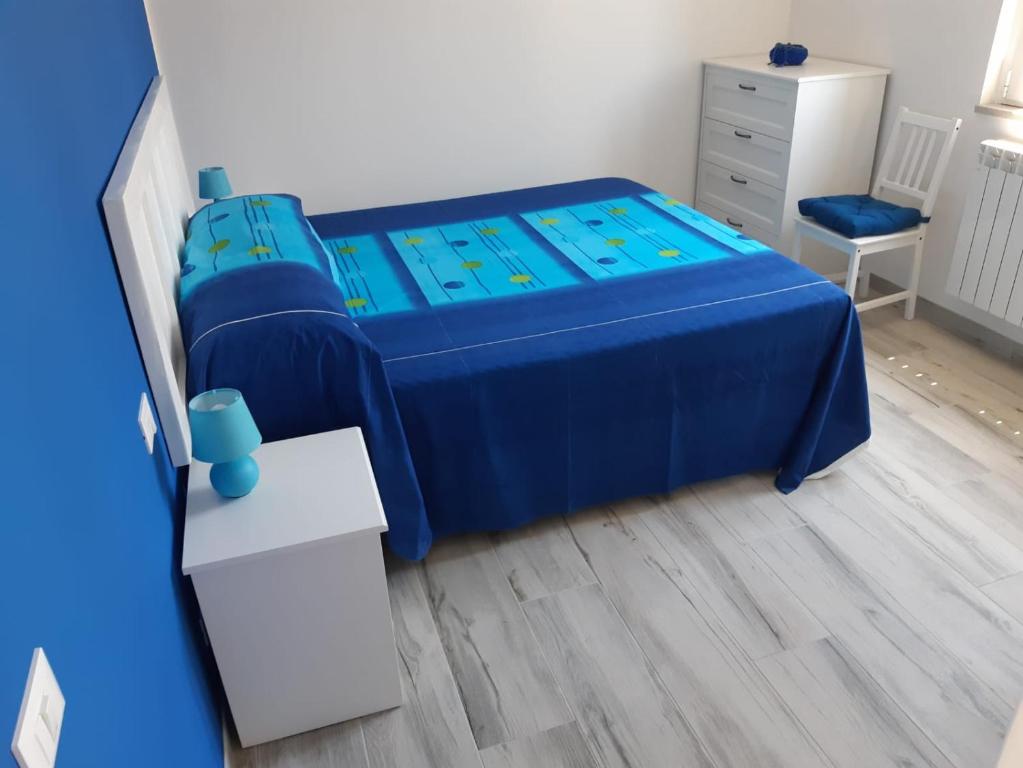 Un pequeño dormitorio con una cama azul y un tocador en I colori del mare, en Villaggio del Pescatore