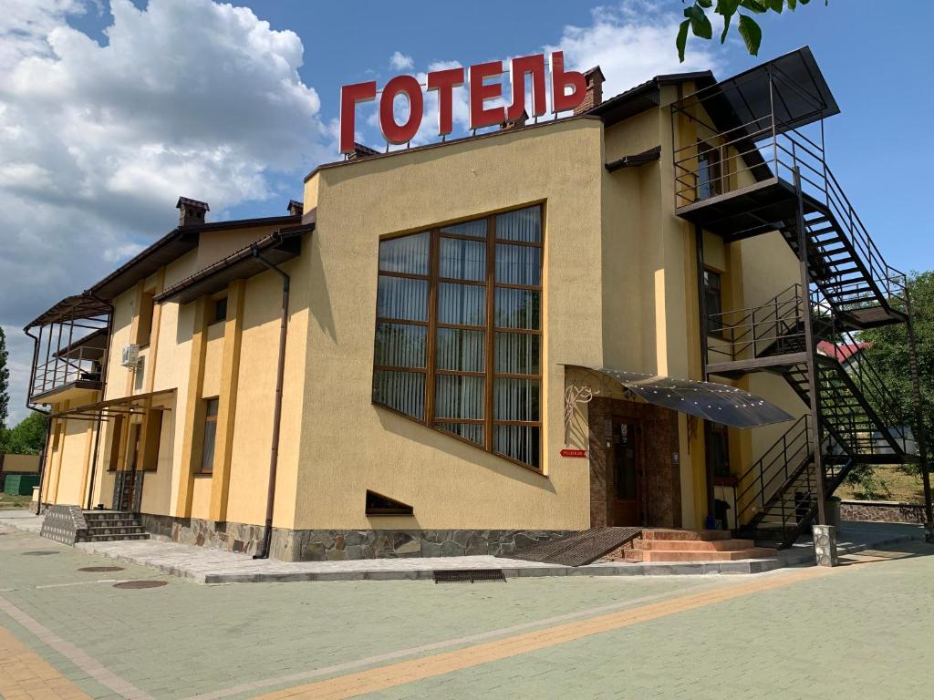 a hotel with a sign on the side of it at Каприз in Kamianets-Podilskyi