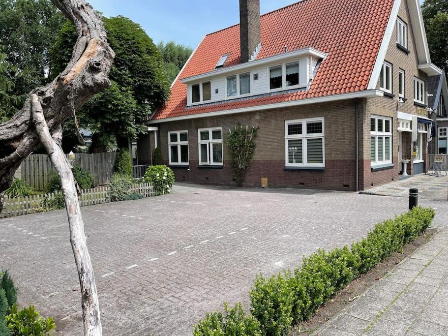 una casa con techo rojo y aparcamiento en Historische gelegen appartement more Days, en Dedemsvaart