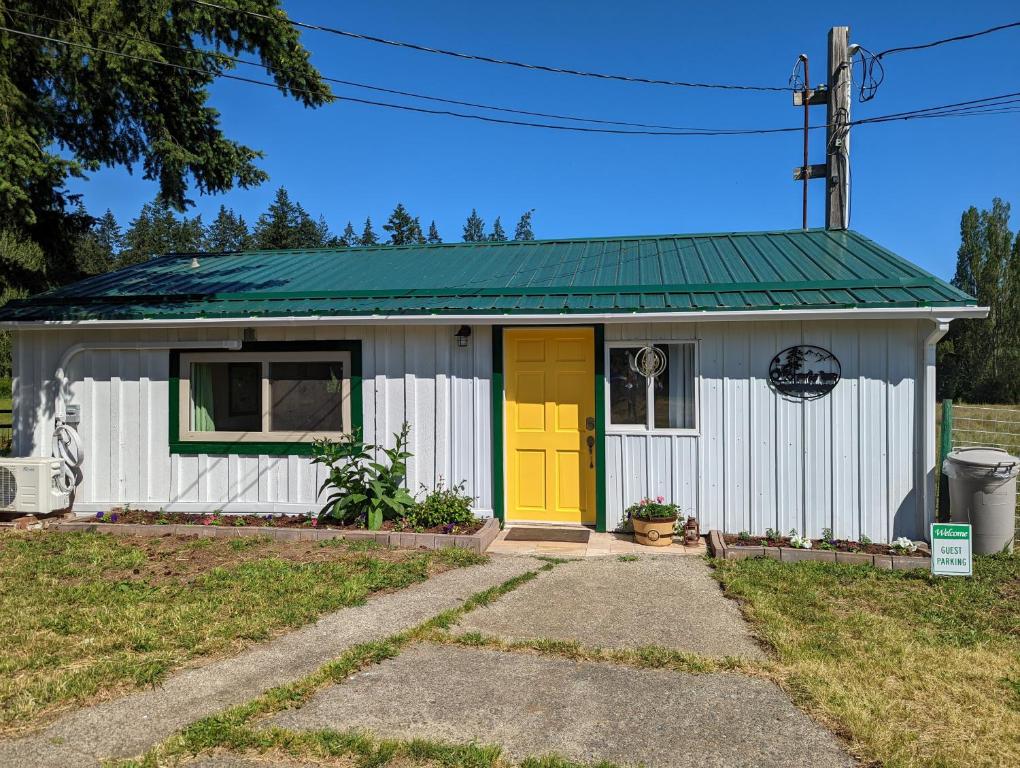 una pequeña casa blanca con puerta amarilla en The Cottage on the Farm en Ladysmith