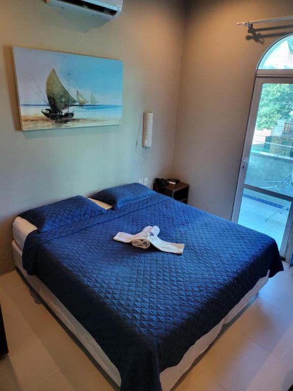 Una cama con un edredón azul y un par de zapatos encima. en Hotel Encontro do Sol, en Fortaleza