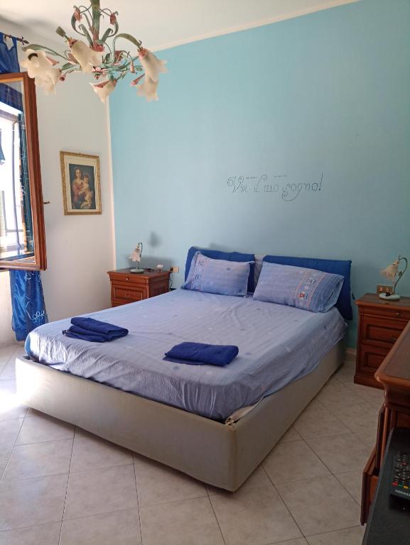 Schlafzimmer mit einem Bett mit blauer Bettwäsche und blauen Kissen in der Unterkunft Casa centro Piombino in Piombino