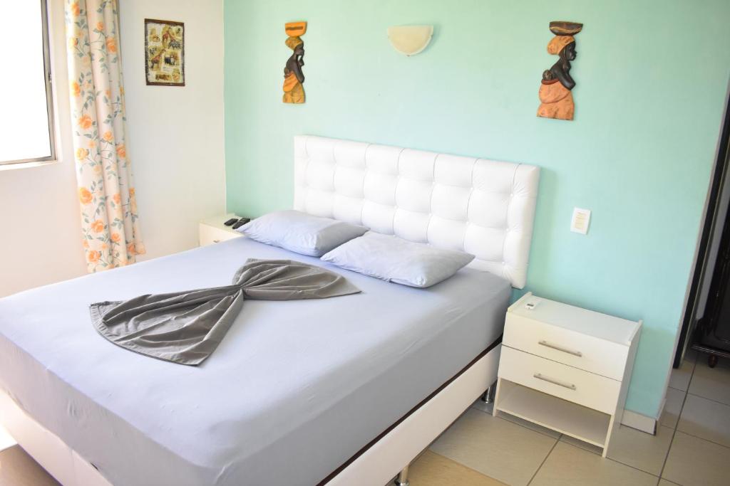 een slaapkamer met een wit bed en een blauwe muur bij Hotel Pousada Rancho Fundo in Camaçari