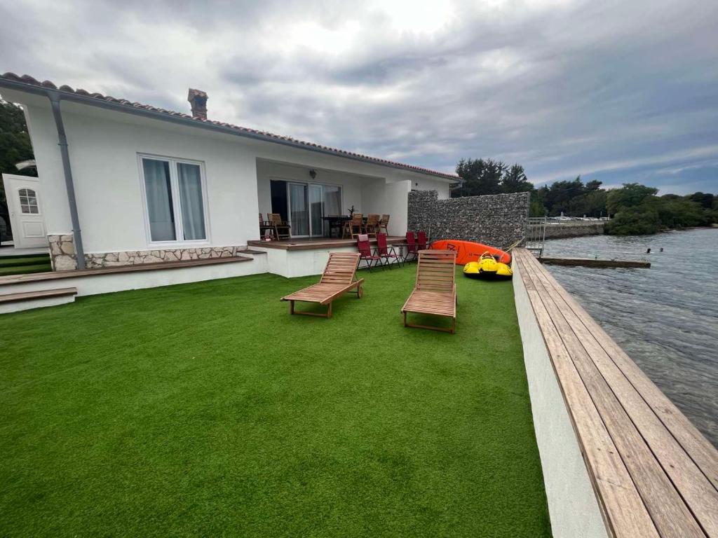 une cour avec des chaises, une maison et de l'eau dans l'établissement Villa Olga - Uniqe house with private beach, à Ankaran