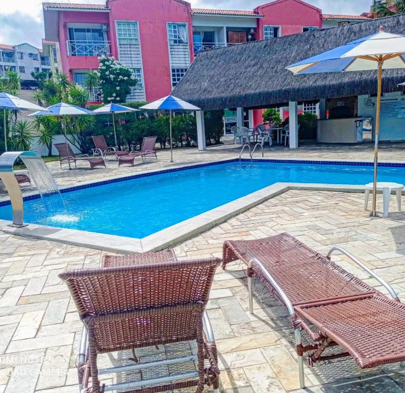 a swimming pool with two chairs and umbrellas at Village Hospedagens in Natal
