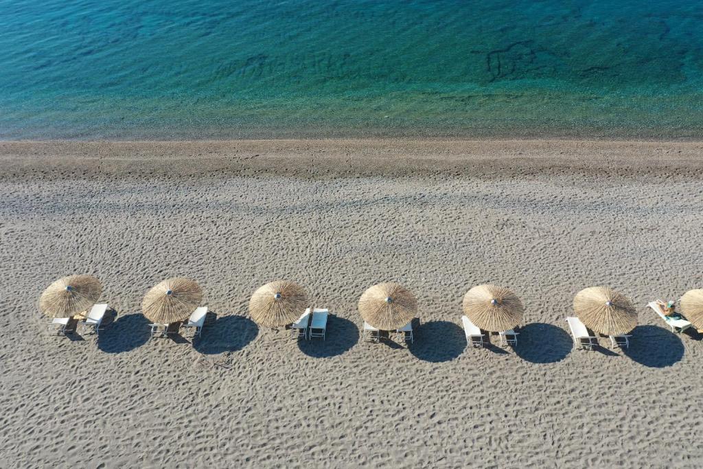 eine Gruppe von Stühlen und Sonnenschirmen am Strand in der Unterkunft Niriides Resort in Gythio