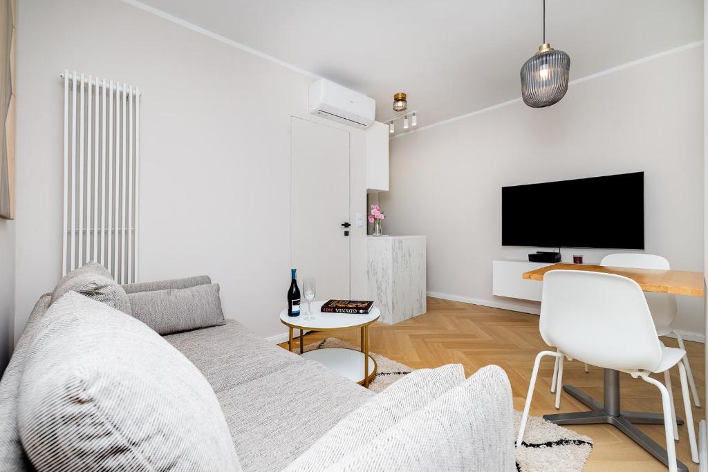 a white living room with a couch and a tv at Apartament w sercu Gdyni in Gdynia