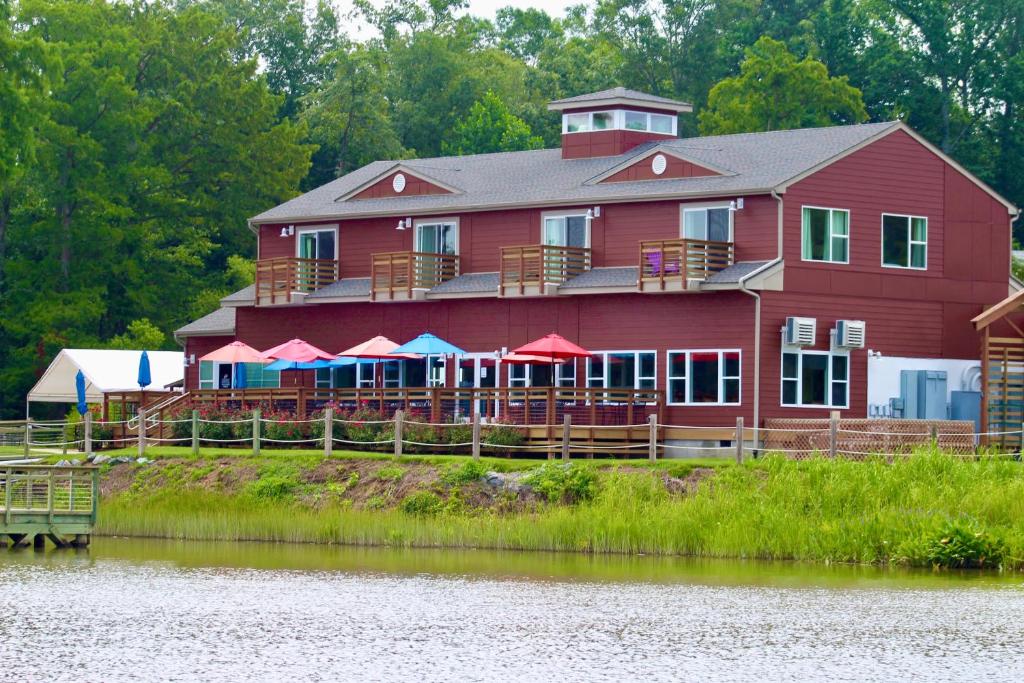 a large red house with tables and umbrellas next to a river at Surry Seafood Company in Surry