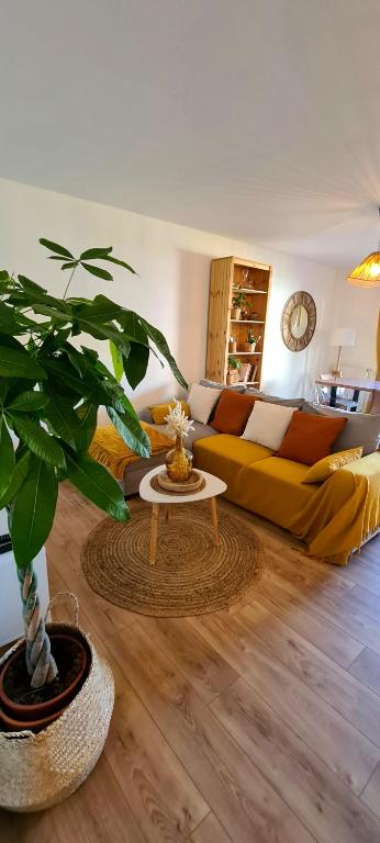 a living room with a yellow couch and a plant at Appartement avec terrasse, parking et proche tramway in Montpellier