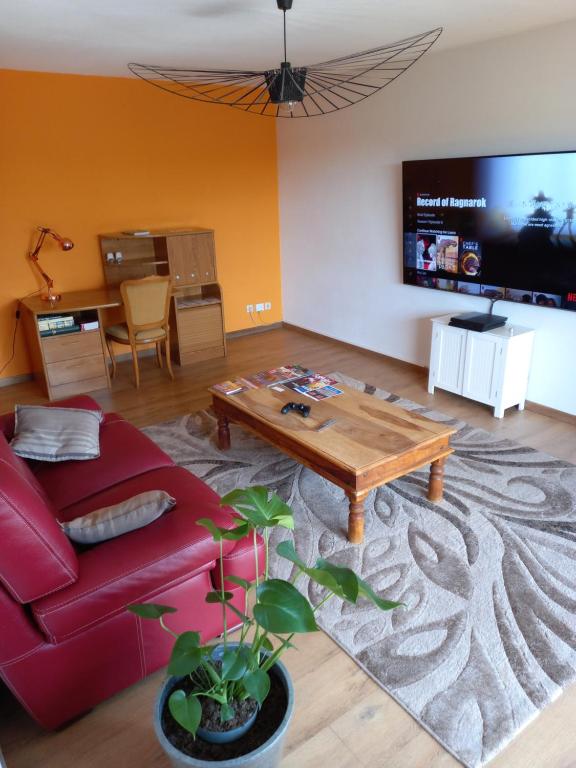 a living room with a red couch and a table at Appartement Blagnac in Blagnac