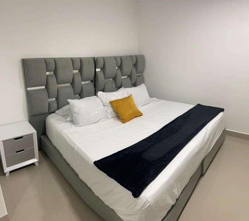 1 cama con cabecero gris y almohada amarilla en Aparta Suites 503 Granada Cali, en Cali