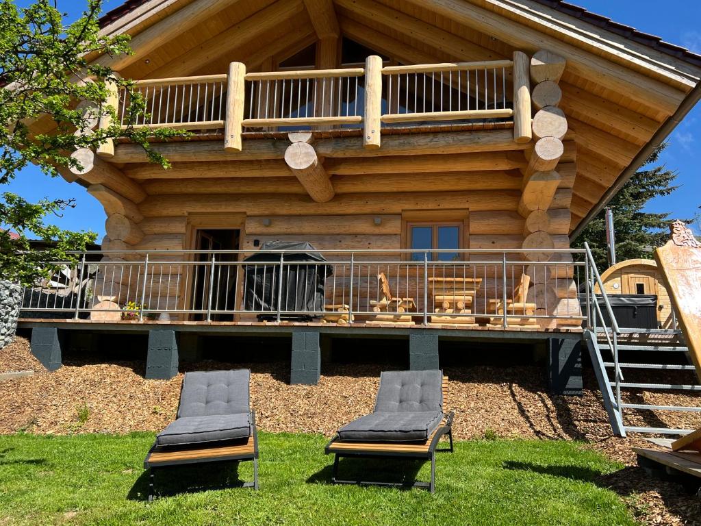 um chalé de madeira com 2 cadeiras e uma varanda em Waldstein Chalet em Zell im Fichtelgebirge