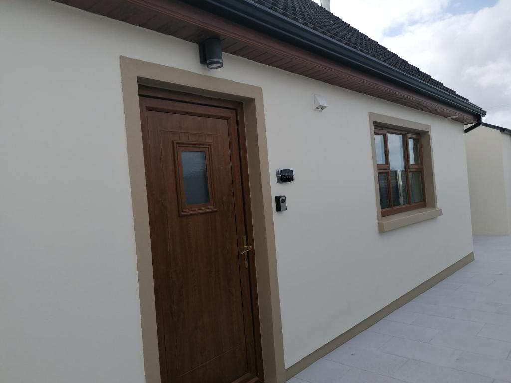 Casa con puerta de madera y 2 ventanas en Atlantic way Apartment 1, en Breaghwy